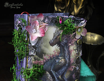 Dettaglio del diario fantasy con drago tra cristalli magici, muschio e fiori giurassici di Fogliaviola Design