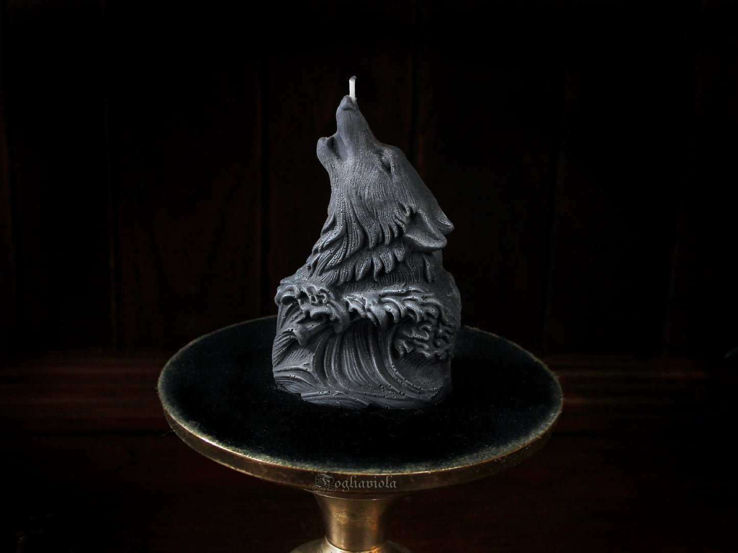 Candela scultura di un lupo grigio che ulula alla luna, emergente da un'onda scolpita, su alzata dorata e velluto nero — atelier Fogliaviola.