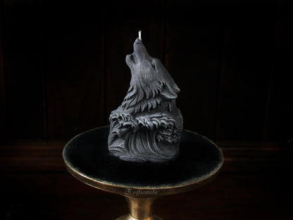 Candela scultura di un lupo grigio che ulula alla luna, emergente da un'onda scolpita, su alzata dorata e velluto nero — atelier Fogliaviola.