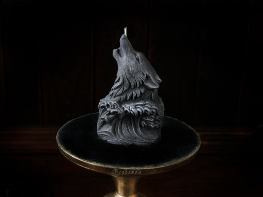 Candela scultura di un lupo grigio che ulula alla luna, emergente da un'onda scolpita, su alzata dorata e velluto nero — atelier Fogliaviola.